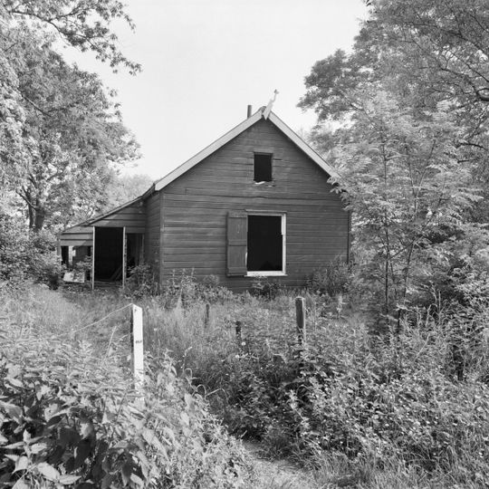 Houten huis zonder verdieping onder pannen zadeldak; in voorgevel een negenruitsschuifvenster met luiken
