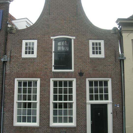 Huis met halsgevel, uitgevoerd in baksteen. Zandstenen voluten