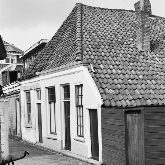 Kleine stadswoning. Gepleisterde voorgevel met lage goot. Schilddak met pannen. Achtergevel aan de Gotte met houten topgevel en vakwerk.