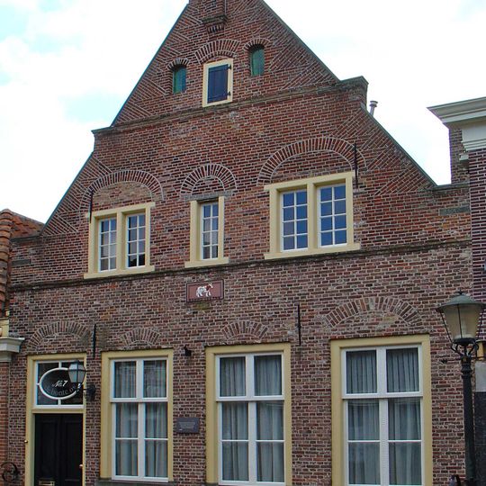 Huis met puntgevel met enkele trappen en uitgekraagde toppilaster