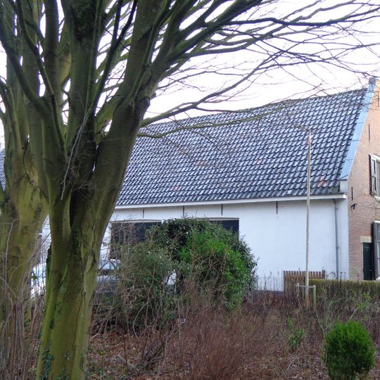 Eenvoudig gepleisterd dwarshuis onder pannen zadeldak