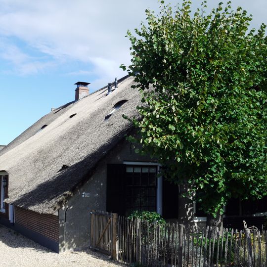 Boerderij met gepleisterde voorgevel met afgewolfd dak
