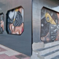 Tres murales representando las manos de un tatuador realizando un tatuaje, un barbero repasando una barba y una esteticista haciendo las cejas a una clienta.