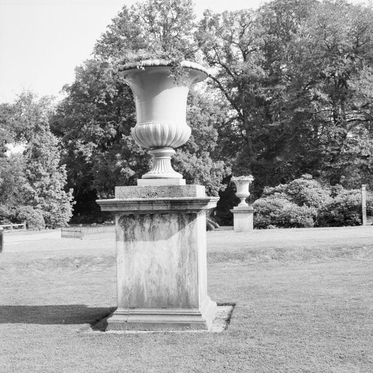 Twickel: twee grote gietijzeren tuinvazen staande op hoge, eenvoudig geprofileerde vierkante op sokkel voorplaats