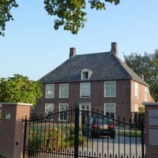 Huis met verdieping onder schilddak, kruiskozijnen van hout met luiken in de achtergevel