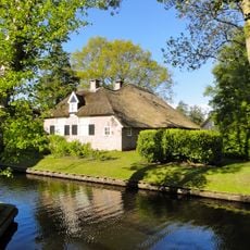 Dwarswoning onder met pannen gedekt schilddak met bedrijfdeel onder rieten schilddak