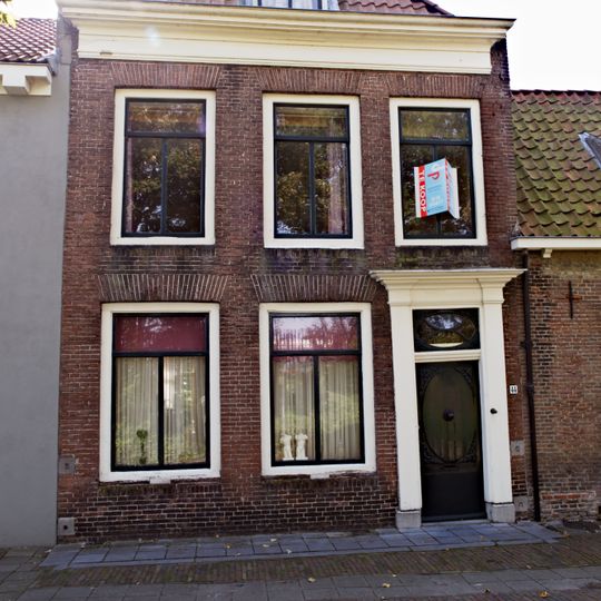 Dwarshuis onder pannen zadeldak met rechts een puntgevel. Twee vensters met 12-ruitsschuiframen. Twee dakkapellen