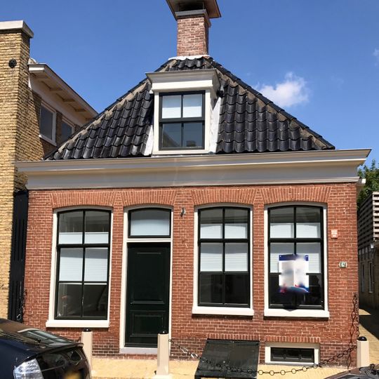 Laag pand onder schilddak met twee hoekschoorstenen met bord