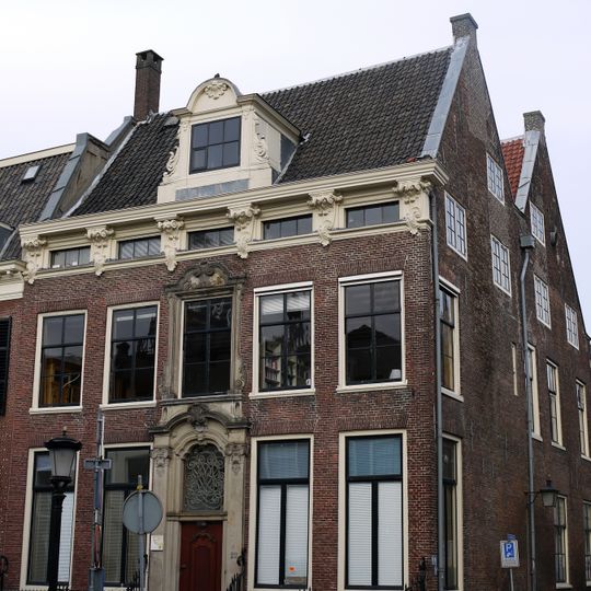 Statig herenhuis met rechte kroonlijst met consoles middenpartij geornamenteerd. Smeedijzeren hekken