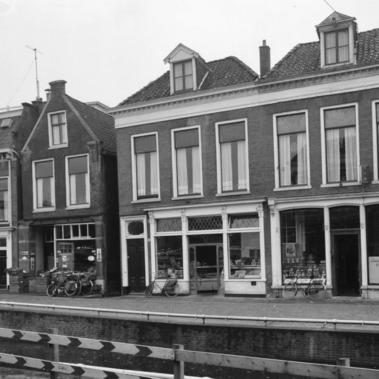 Pand met gepleisterde lijstgevel met zesruits vensters en deurkozijn met zijlichten