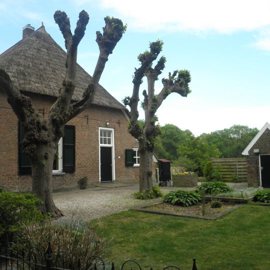 "Elmerink": boerderijtje onder gedeeltelijk met riet gedekt wolfdak. In de voorgevel datering in jaarankers 1774. Varkensstal van hout en baksteen onder een gedeeltelijk met riet gedekt wolfdak.