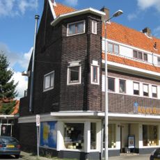 Blok met winkels met brede luifel en daarboven woningen, bouwstijl Amsterdamse School, onderdeel van het centrale achthoekige plein van Tuindorp Nieuwendam