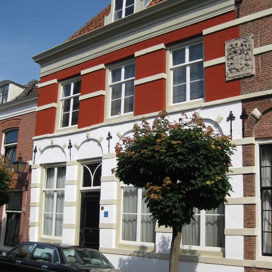 Pand met lijstgevel, natuurstenen banden en bogen boven vensters, beneden vensters met maskers