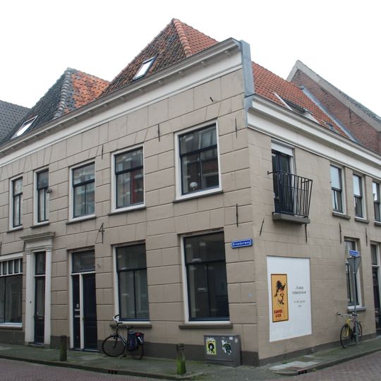 Hoekhuis met trapgevel met speklagen en door pinakel op gebeeldhouwd kraagsteentje bekroond