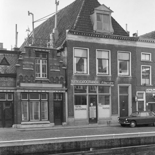 Eenvoudig pand met verdieping geblokte kroonlijst onder hoog zadeldak met voorschild en dakkapel