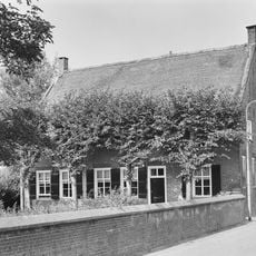 Een statige hoeve, T-huis, waarvan het rechts onderkelderde woonhuis een verdieping en een rieten zadeldak bezit