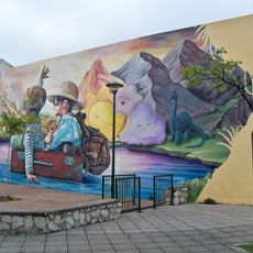 Mural que presentan dos niños navegando en una maleta sobre las aguas de una laguna prehistórica imaginaria.