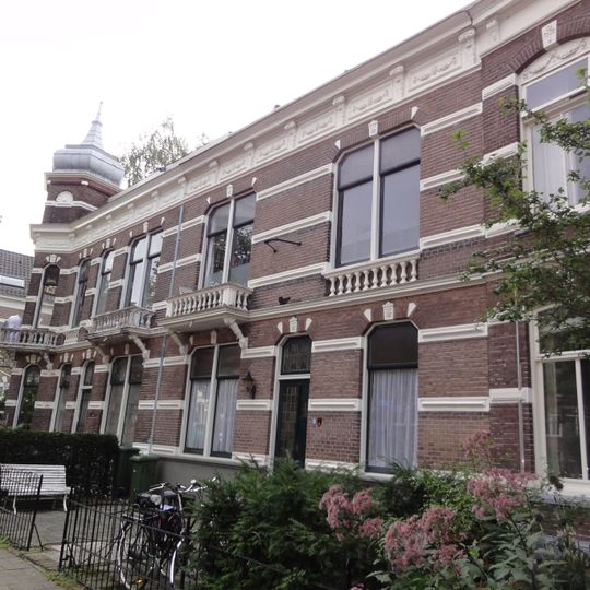 Blok met woonhuis, beneden- en bovenwoning met een door een eenvoudig smeedijzeren spijlenhek omzoomde voortuin