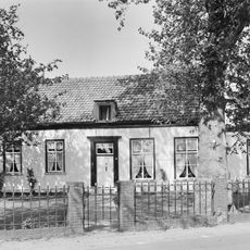 Dwarshuis onder zadeldak; zesdelige Empire schuiframen, omlijste ingang, gepleisterde gevel