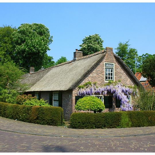 Lage arbeiderswoning onder een rieten zadeldak, eindigend in topgevel