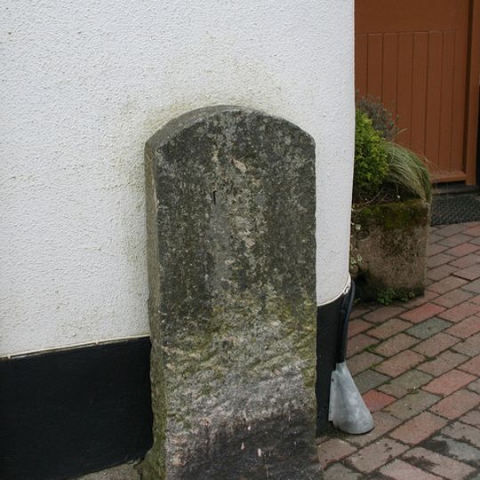 Milestone, opp. church entrance, beside shop wall, opp Burrington Post Office
