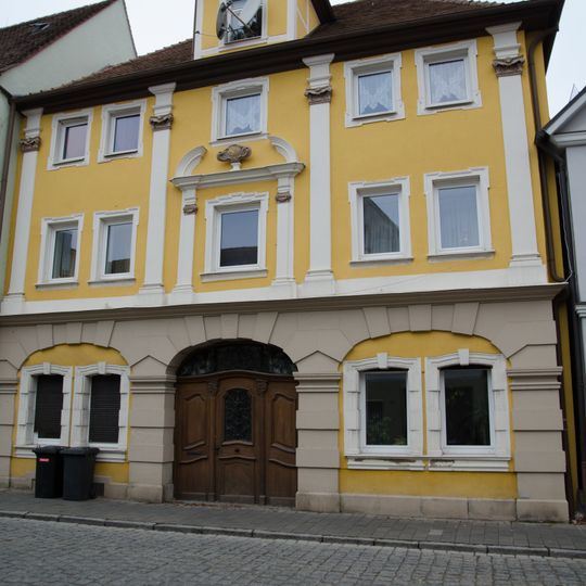 Fassade eines reich gegliederten dreigeschossigen Bürgerhauses und Holztor