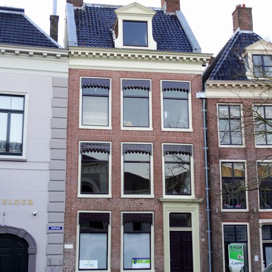 Pand met twee verdiepingen, hoog dwarsdak tussen topgevels, hoekschoorstenen, geblokte kroonlijst en dakkapel