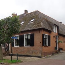 Boerderij waarvan het muurwerk gedeeltelijk bestaat uit waarschijnlijk van sloop afkomstige moppen. Rieten schilddak, oude kozijnen