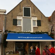 Huis met tot puntgevel met rollaag gewijzigde trapgevel met geprofileerde zij-afdekstukken