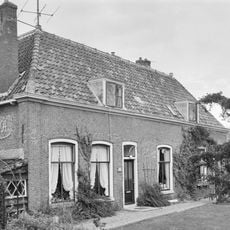 Dwarshuis, zonder verdieping en met pannen schilddak, waarin twee dakkapellen met geprofileerde lijsten. Gemetselde hoeklisenen. Geprofileerde gootlijst; getoogde vensters, eenvoudig bovenlicht