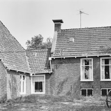 Kop-hals-rompboerderij met onderkelderd woonhuis onder zadeldak met twee topschoorstenen met borden en met beeldbepalende schuur onder zeer groot dak