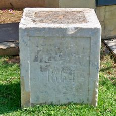 Resto de lo que parece ser un basamento rectangular de columna o pilar. En una de sus caras aparece inscrito el año «1864».