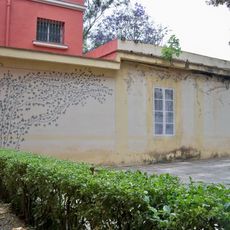 Mural en un edificio anexo a la Hacienda Nadales que representa una planta trepadora que parece surgir del seto y unas ventanas que imitan las ventanas de la Hacienda San José que se encuentra junto al edificio de la Hacienda Nadales.