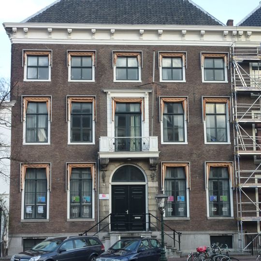 Pand met bakstenen gevel met rechte kroonlijst met consoles. Hardstenen deuromlijsting, stoep met palen en verhoogde voordeurstoep