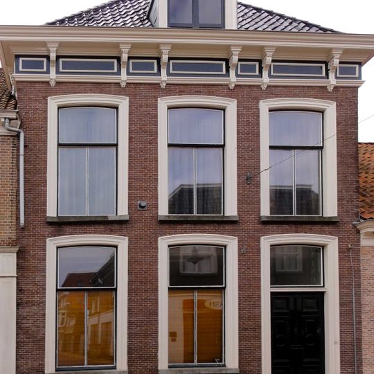 Woonhuis met bakstenen gevel en rechte kroonlijst met consoles en panelen onder schilddak met hoekschoorstenen