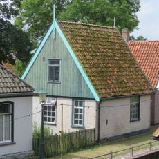 Pand met gepleisterde muren; zadeldak met nok evenwijdig aan de rooilijn. Houten zijgeveltopbeschietingen
