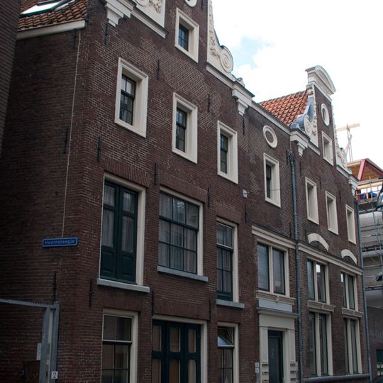 Pand met twee halsgevels met gebeeldhouwde vleugelstukken en gebogen frontons en met gewijzigde onderbouw