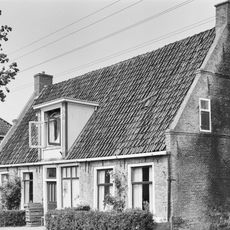 Pand onder zadeldak tussen twee topgevels met waterlijsten, beitelingen langs de zijden en ieder twee kleine lichtopeningen met luiken