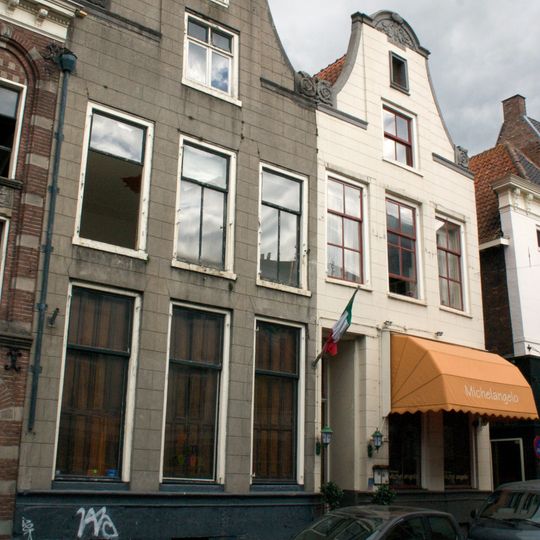 Dubbel pand met twee identieke gepleisterde halsgevels met gebeeldhouwde halfronde topafdekking en aanzetvoluten