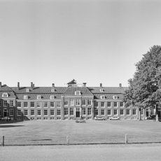 Pand met vooruitspringende sobere lijstgevel, dak door schoorstenen bekroond