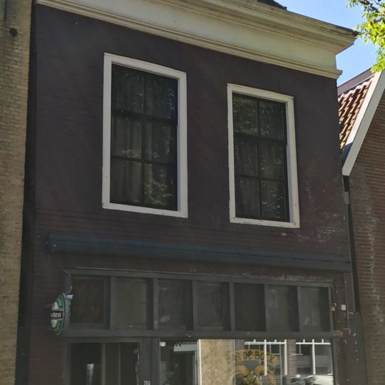 Pand onder diep zadeldak met voorschild en schoorsteen met bord