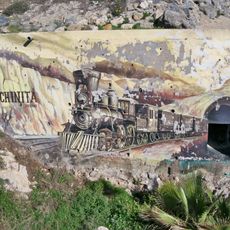 Mural que representa al antiguo tren de los Ferrocarriles Suburbanos de Málaga, conocido popularmente como 'El Matagallinas' o 'La Cochinita'. En el mural, se lee: «La Cochinita / (1908-1968)».