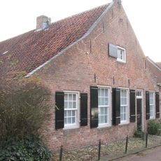 Gepleisterd laag huis, boerderij, luiken aan de ramen, brede topgevel