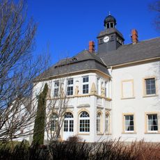 Herrenhaus einschließlich seitlich angebauter Mauer und zwei gemauerte Pfosten mit geschweiften Aufsätzen als Einfriedung (Einzeldenkmal zu ID-Nr. 09251509); Hauptstraße 11