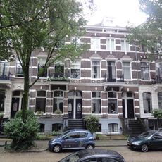 Rij van aaneengesloten herenhuizen (beneden- en bovenwoningen) met hekken