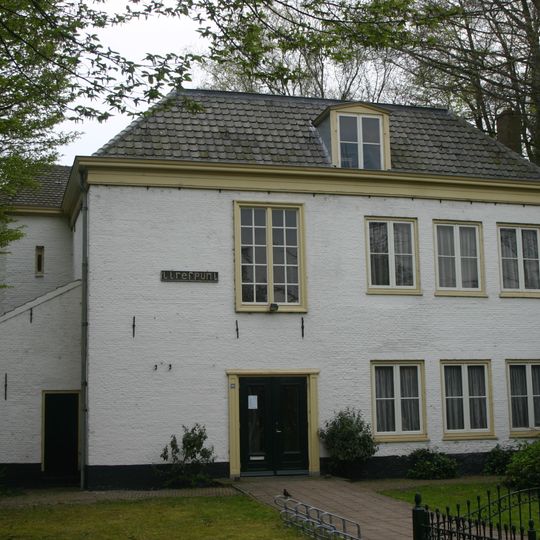 Voormalige pastorie naast de kerk; rechthoekig cremekleurig gebouw