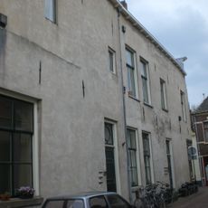 Omvangrijk, uit twee bouwlichamen samengesteld, in aanleg laat-gotisch hoekhuis