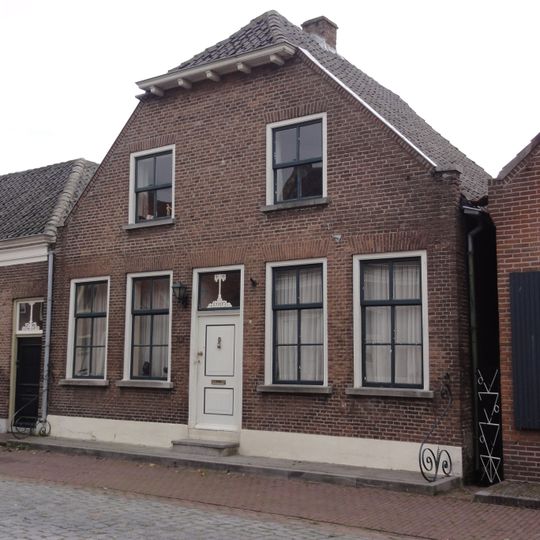 Huis onder breed zadeldak, aan de voor- en achtergevel afgewolfd