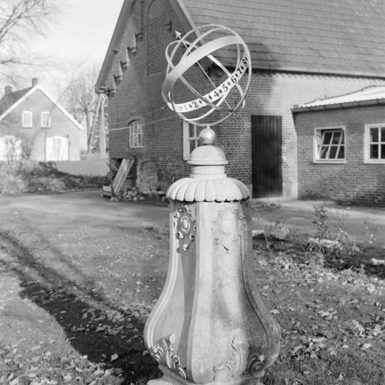 Een zonnewijzer op een gebeeldhouwd natuurstenen voetstuk in Lodewijk XV stijl