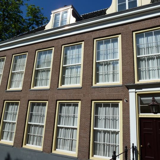 Pand met gevel met rechte kroonlijst. Onder zelfde nr 37, poort bekroond door twee marmeren busten